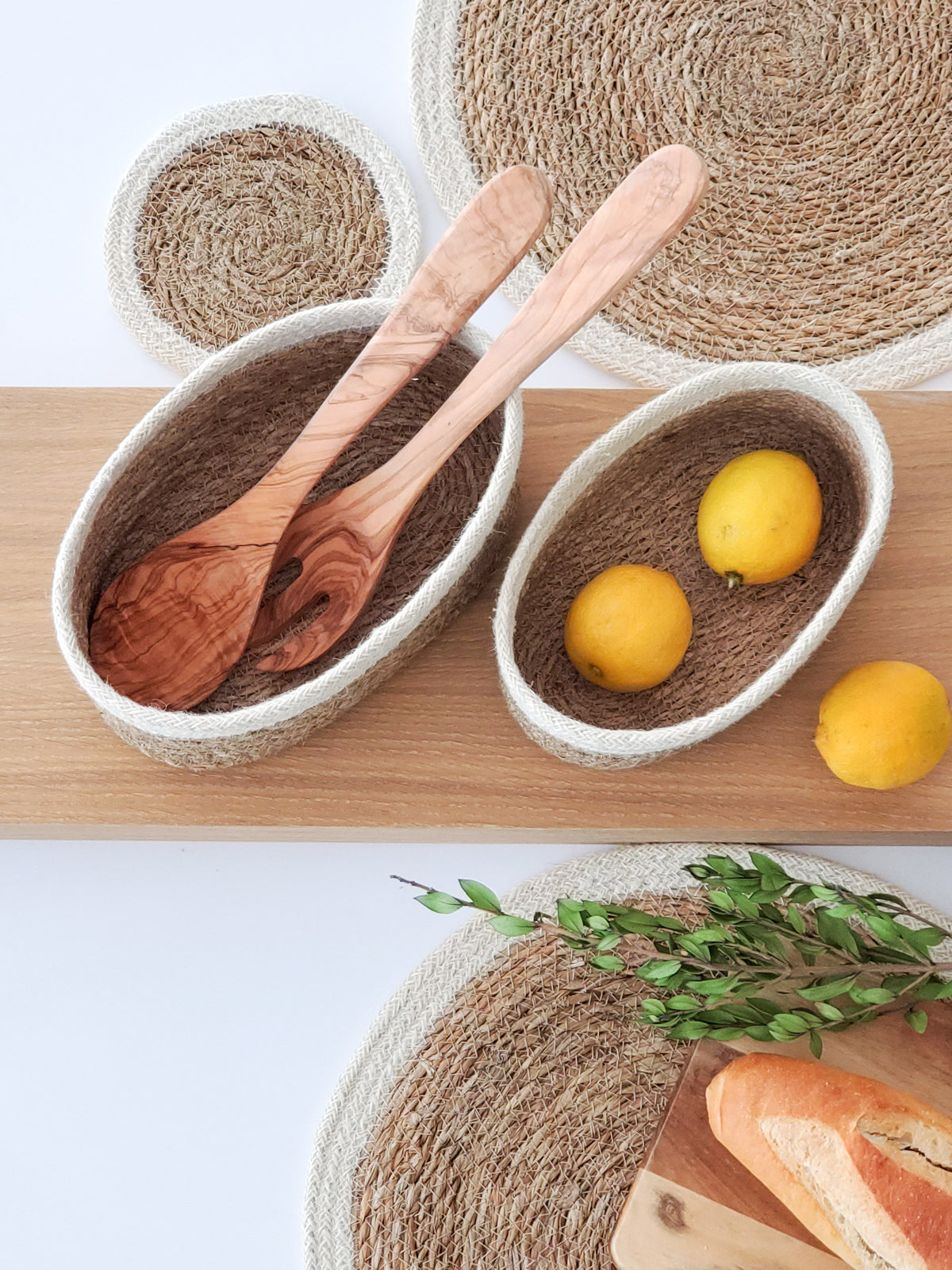 Wooden spoons in a woven bowl with lemons on a wooden surface.
