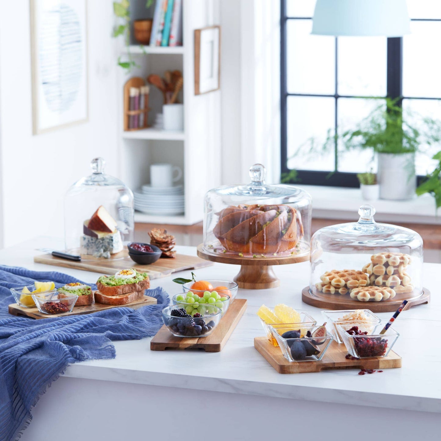 Dessert display with glass cloches and various treats on a kitchen counter.