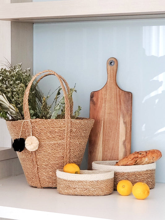Woven baskets, cutting board, and bread on a kitchen counter with a light blue wall in the background.