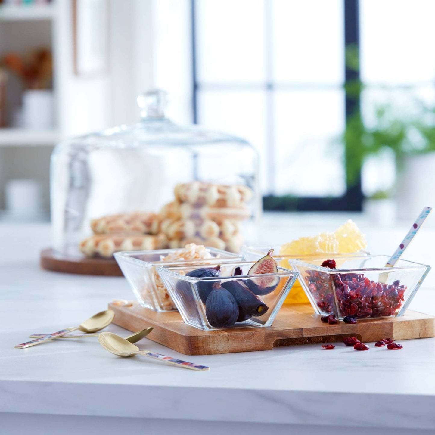 Glass bowls with figs and berries on a wooden board with a blurred background