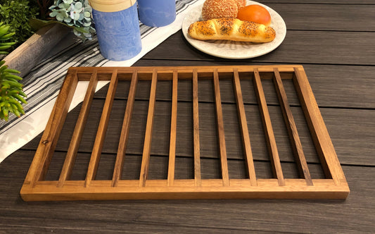 Wooden tray on a wooden surface with a plate of food and cups in the background.